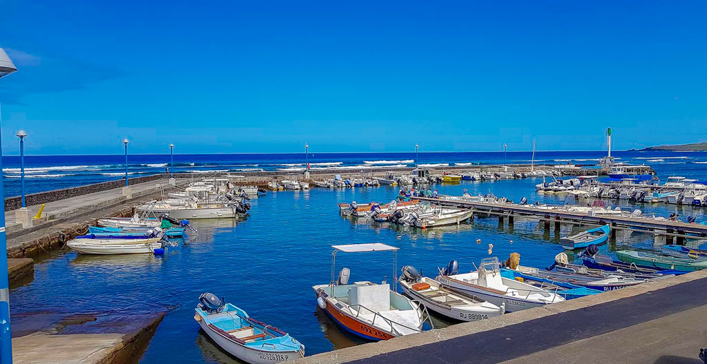 Front de mer de Saint-Leu avec ses cases créoles colorées, surfeur revenant de session et océan Indien en arrière-plan sous lumière dorée de fin de journée